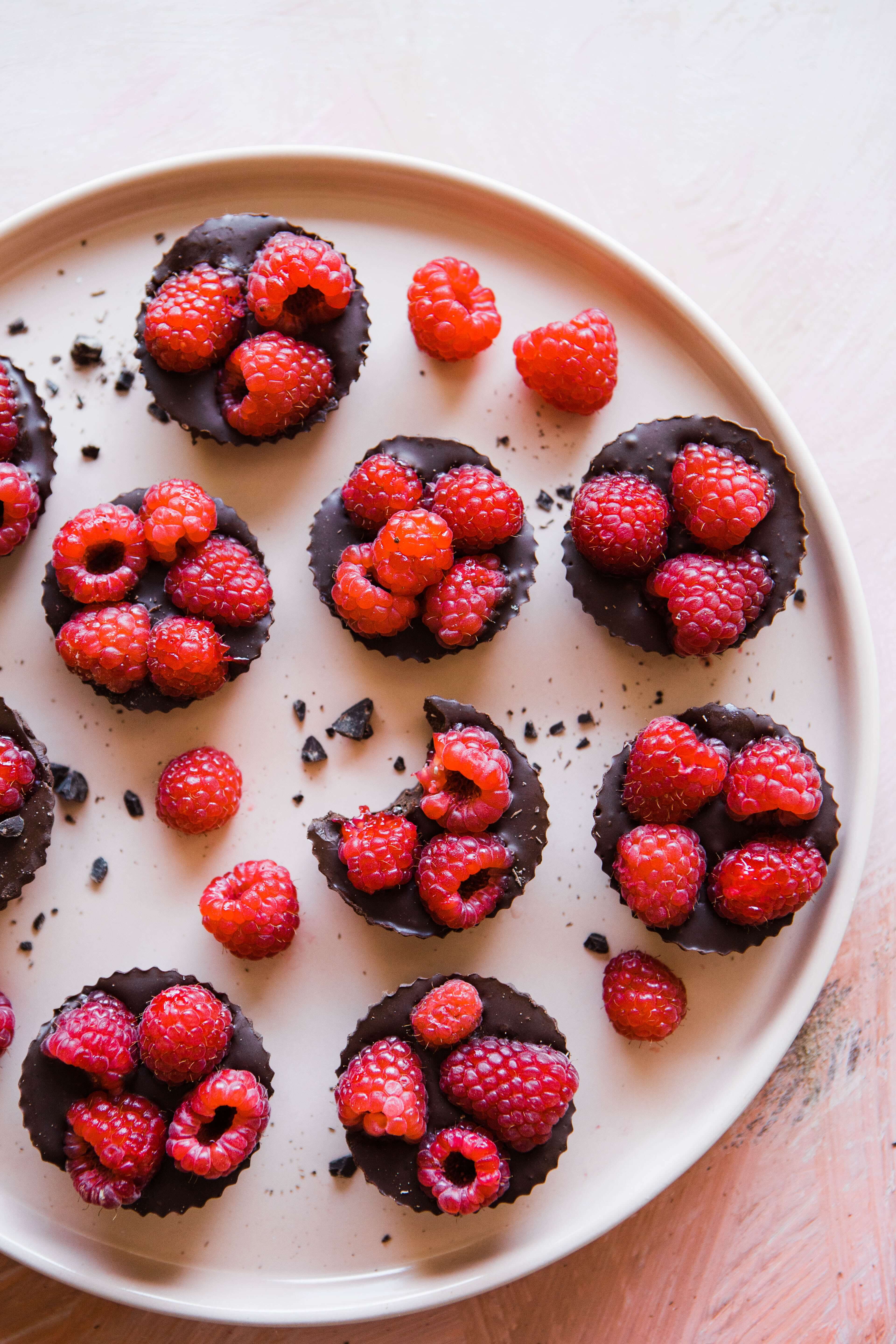 Delicious red raspberries atop chocolate pastries in a serving dish.